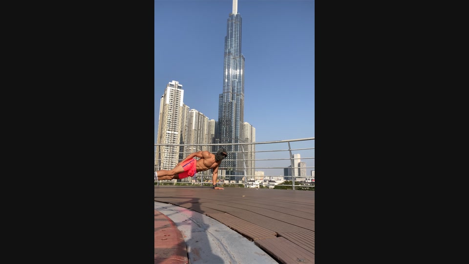 Outdoor side-plank training documented against a high-rise skyline in daylight.